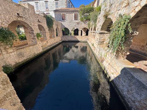 Stone courtyard with a clear water pool and stone arches.