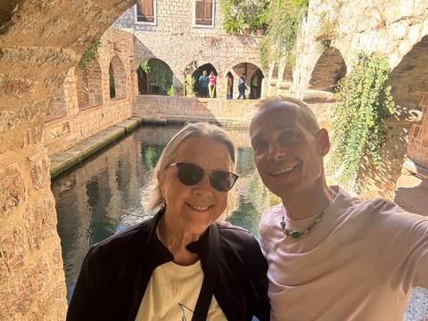 Two people posing in a stone courtyard with water features.