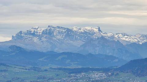 Mountain range with snow-capped peaks under a cloudy sky.