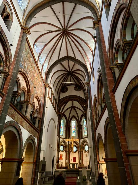 Interior of a church with arches and stained glass windows.
