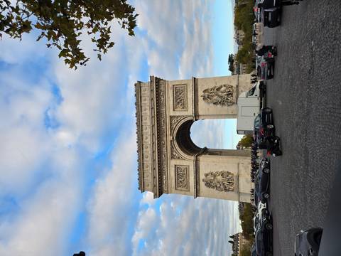 Arc de Triomphe with traffic in front and a cloudy sky.