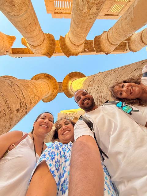 Four people smiling with two ancient columns in the background.