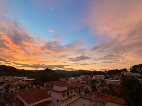       Colorful sunset over a town with hills in the background.
  