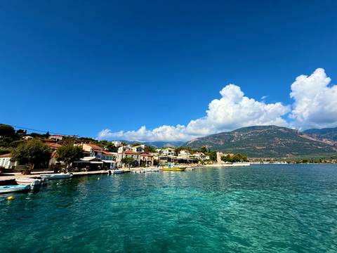       Coastal village with buildings by the sea and mountains in the background.
  
