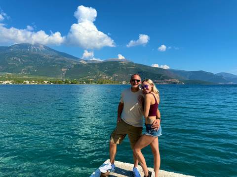      Couple posing by a large body of water with mountains.
  