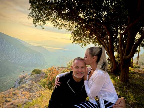       Couple embracing under a tree with a scenic view.
  