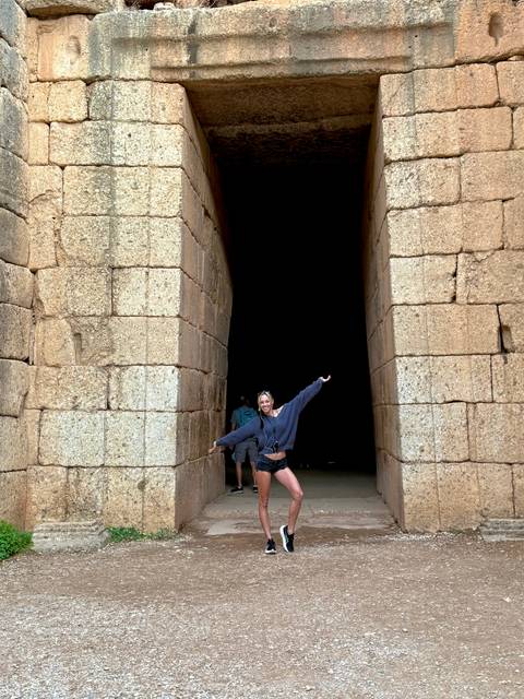       Person posing in a stone archway.
  