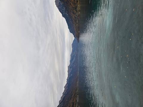       Calm lake with mountains in the backdrop under a cloudy sky.
  