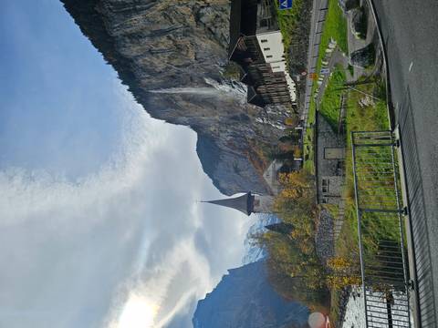       Historical architecture against a mountainous backdrop with waterfall.
  