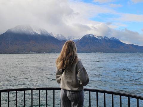Person gazing at a lake with majestic mountains in the distance.