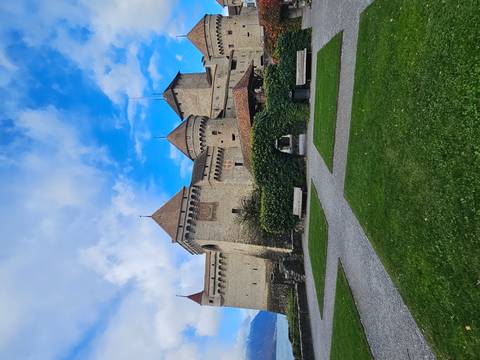 Medieval castle with manicured gardens and a blue sky.