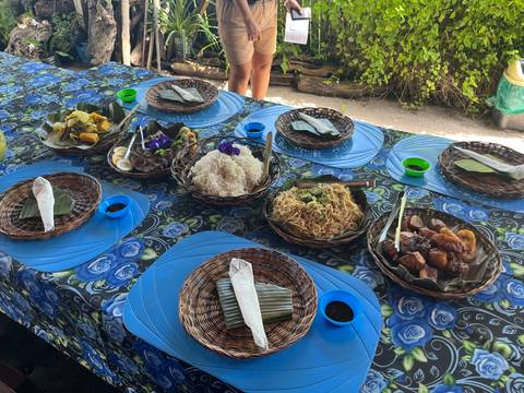 Outdoor meal setup with various dishes and blue tablecloth.