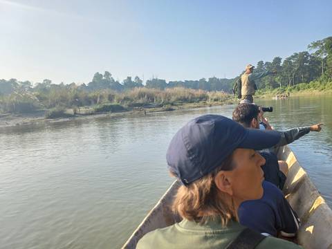       People on a boat exploring a river with an adventurer standing.
  