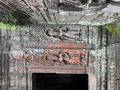 Stone wall with intricate carvings and moss growth