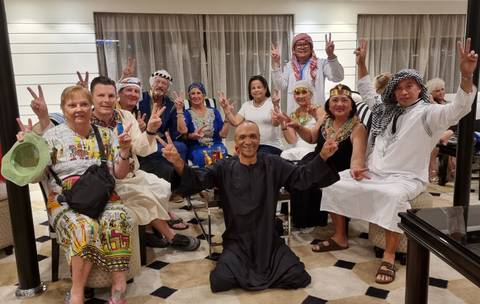 Group of tourists in traditional clothing posing indoors.