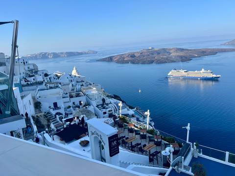 Stunning view of a Mediterranean island with white buildings and a cruise ship in the sea.