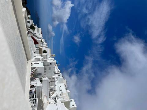       White buildings on a hill with clear blue skies.
  