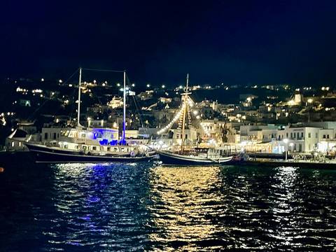       Night view of a harbor with sailboats and lit buildings.
  