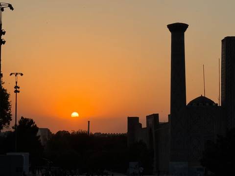 Silhouette of buildings at sunset with an orange sky.