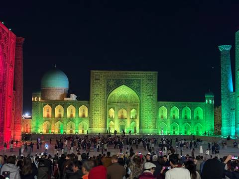       Registan illuminated at night with visitors.
  