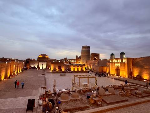       Historic square with illuminated buildings and visitors.
  