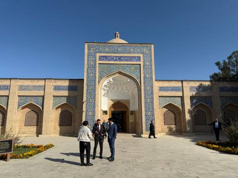 People at a historic building entrance with ornate blue designs.