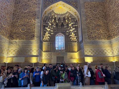 Tourists looking at an intricately designed interior with high ceilings.