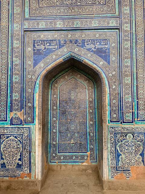       Ornate blue and green tile work on an arched door.
  