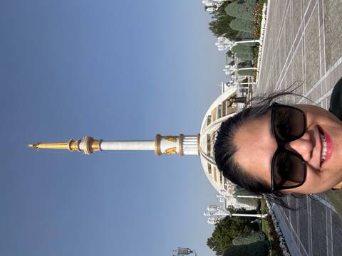      A person taking a selfie in front of an ornate column in a city square.
  