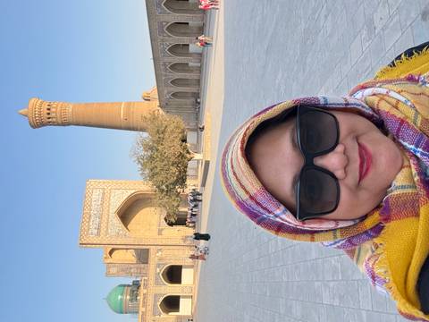 A person posing in front of a historic architectural site in a city square.