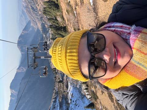       A person on a ski lift in a mountainous area.
  