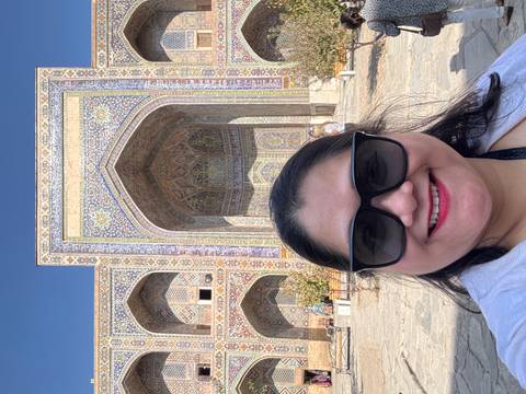 A person posing in front of an ornate architectural entrance.