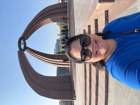       A person standing in front of a monumental structure with a wreath.
  