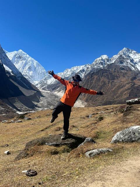       Man posing with snowy mountain range in background.
  