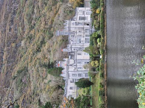 Castle-like building surrounded by trees by a lake.