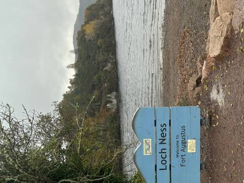       Lake view with a sign saying 'Loch Ness' and trees in the background.
  