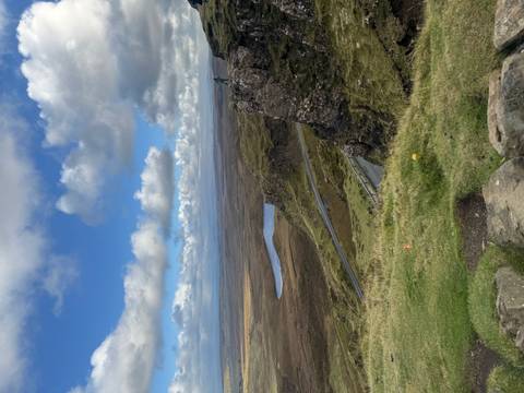       Vast landscape with rolling hills and a solitary person on a cliff.
  