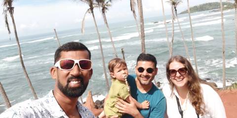 Group of people taking a selfie at the beach with palm trees.