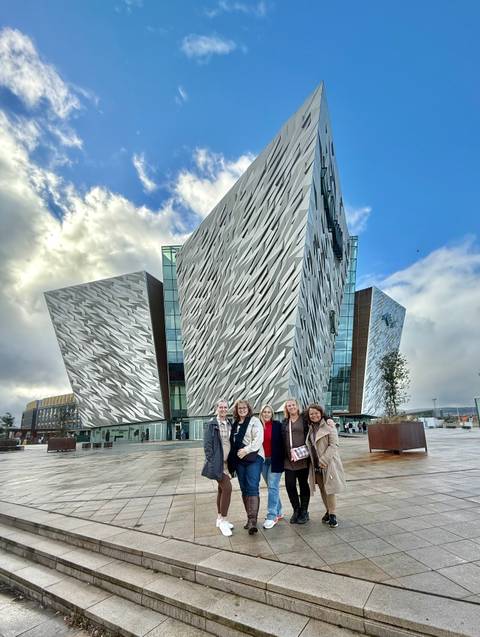 Group of people posing in front of a modern architectural building.