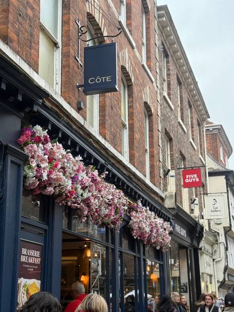 Exterior of a building with floral decorations and store signs.