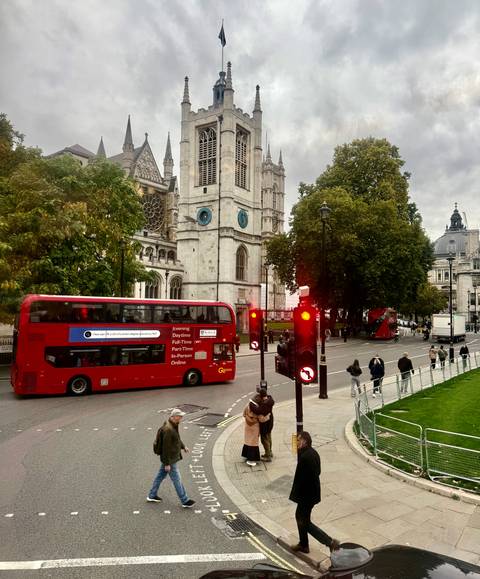 Red double-decker buses in city street near gothic architecture.