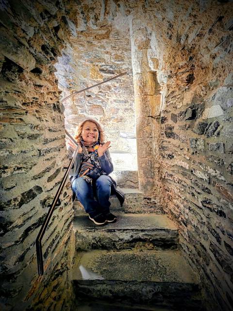 Person posing on a stone staircase indoors.