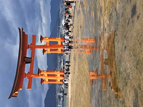 Tourists walking in front of the Itsukushima Shrine gate.