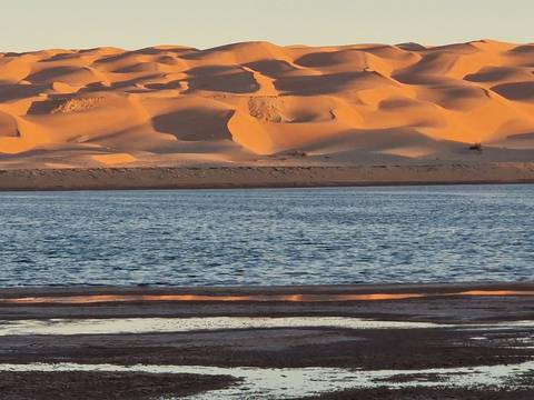 Desert dunes near a body of water.