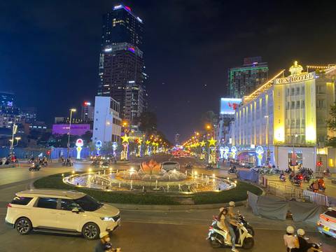 Illuminated city street in Ho Chi Minh City at night with traffic and buildings.
