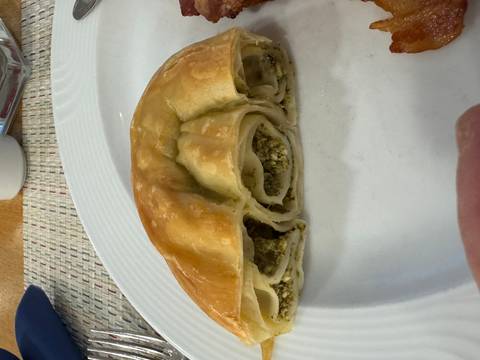       A slice of savory pastry filled with cheese and herbs on a plate.
  