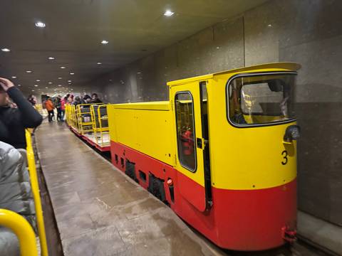       Underground yellow train with people boarding.
  
