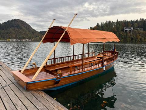       Wooden boat docked by the lake with mountains in the background.
  