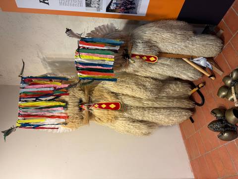       Two traditional Slovenian Kurent costumes with colorful streamers on top.
  
