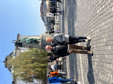       Two people standing in front of a statue in a public square.
  